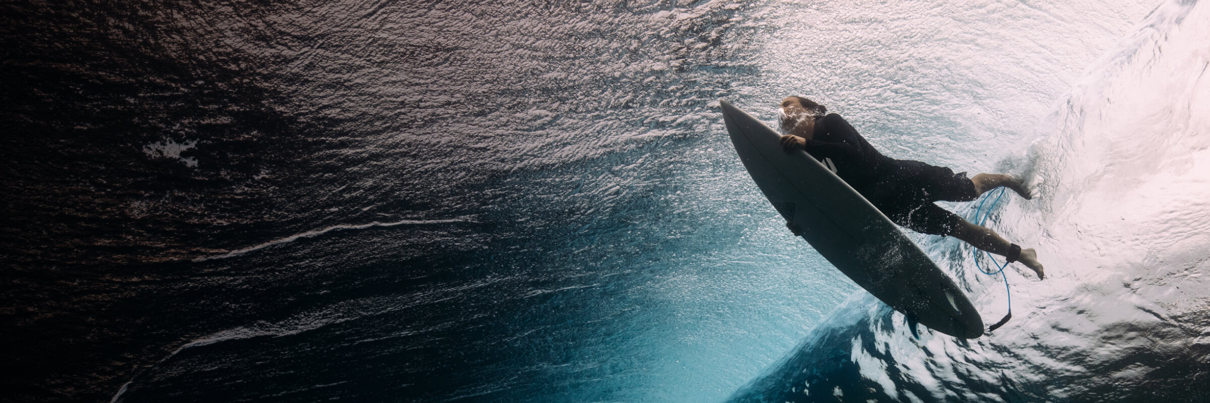 Ein Surfer taucht unter einer Welle durch