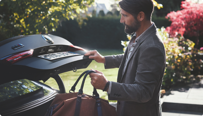 Geschäftsmann holt Gepäck aus dem Kofferaum eines BMWs