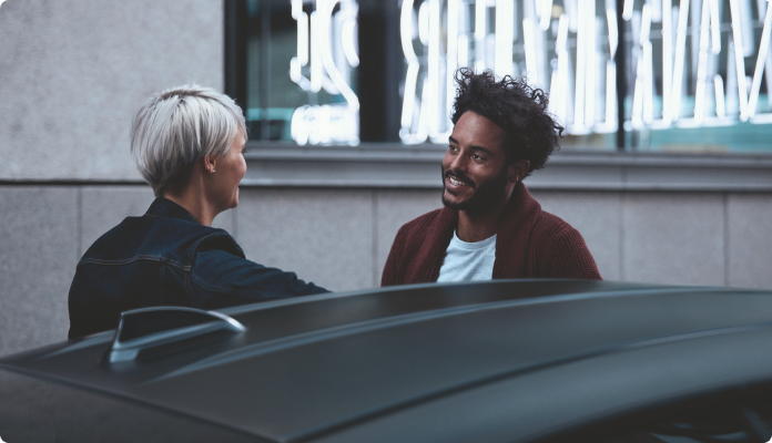 Zwei Personen stehen am Auto und unterhalten sich