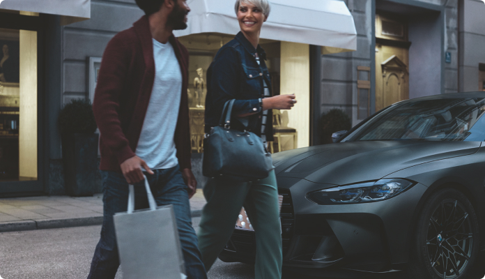 Zwei Personen mit Einkäufen gehen zum Auto