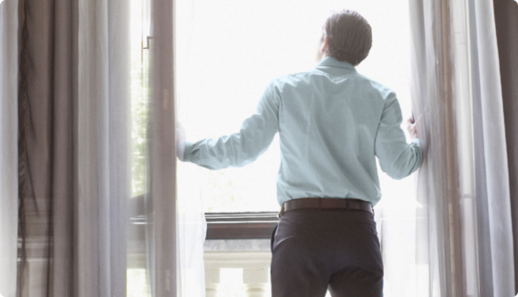 Mann steht im Hotel am offenen Fenster
