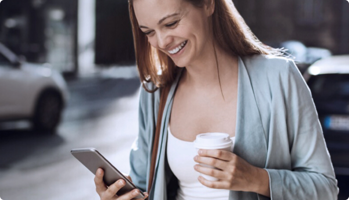 Frau mit Kaffee und Smartphone in der Hand